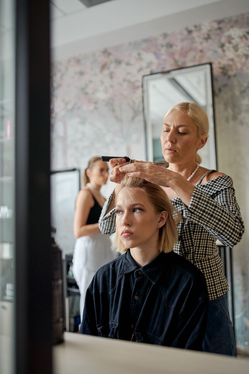 Friseurin richtet das Haar einer Kundin mit einem Glätteisen